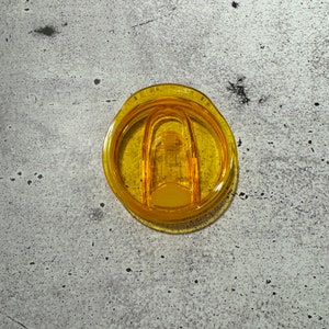 May include: A yellow plastic lid for a travel mug with a clear plastic slider.