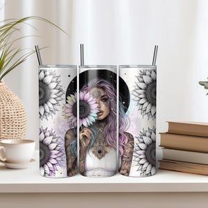 May include: Three stainless steel tumblers with a white background and a design of a woman with a sunflower behind her. The woman has pink hair and tattoos. The sunflowers are black and white with a rainbow colored center.