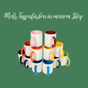 Pu&ograve; includere: Una pila di tazze in ceramica bianca con bordi e manici colorati. Le tazze sono disposte a forma di piramide. Il testo "Mehr Tassenfarben in meinem Shop" &egrave; scritto sopra le tazze.