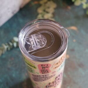 May include: A stainless steel tumbler with a clear lid and a motivational quote design. The tumbler features a variety of colorful text in a playful font, including "It's okay to have bad days".