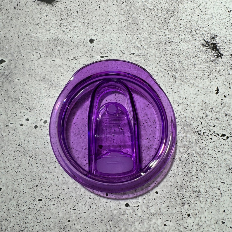 May include: Purple plastic lid for a travel mug with a sliding closure.