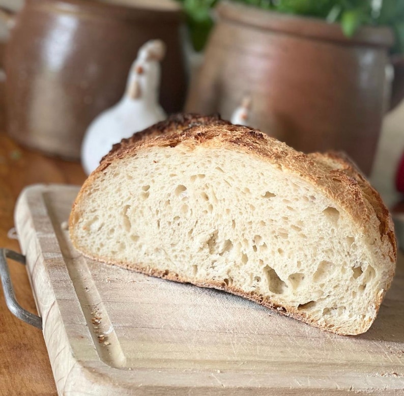 May include: A close-up of a freshly baked loaf of bread sliced in half, revealing a soft, airy crumb. The bread is on a wooden cutting board.