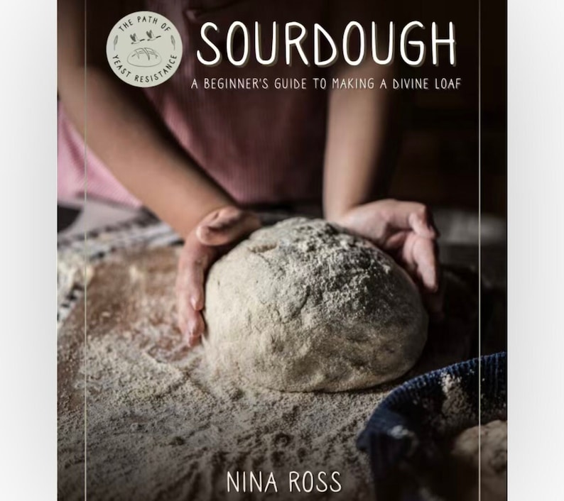 May include: A book cover with the title "SOURDOUGH: A Beginner's Guide to Making a Divine Loaf" by Nina Ross. The cover features a close-up of a hand shaping a loaf of sourdough bread.