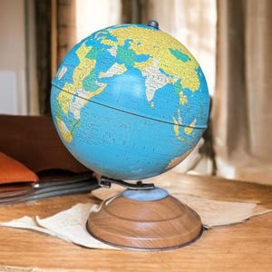 Może przedstawiać: Zabytkowy globus z niebieskim oceanem i żółtymi i zielonymi lądami. Globus jest zamontowany na drewnianej podstawie z metalowym wspornikiem. Klasyczny przedmiot edukacyjny i dekoracyjny.