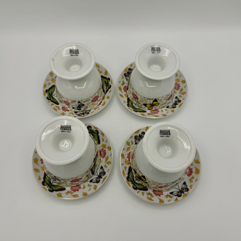 Peut inclure: Ensemble de quatre tasses &agrave; th&eacute; et soucoupes en c&eacute;ramique blanche avec un motif de papillon. Les tasses et les soucoupes ont une bordure dor&eacute;e et pr&eacute;sentent une vari&eacute;t&eacute; de papillons color&eacute;s sur un fond blanc. Le fond de chaque tasse porte l'inscription "Bioloux Turner Made in China."