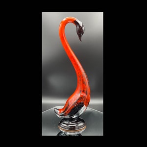 Puede incluir: Una figurita de cisne de cerámica roja y negra con un cuello largo y una base detallada. El cisne está en una pose elegante con la cabeza inclinada hacia un lado.