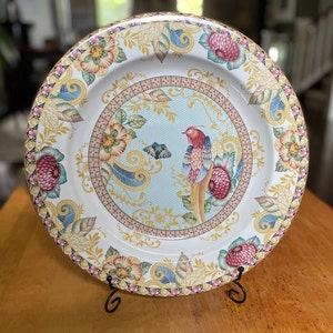 Peut inclure: Une assiette en céramique blanche avec un motif floral et un oiseau coloré. L'assiette a un bord surélevé et un bord festonné. Le motif représente un oiseau bleu à longue queue, des fleurs roses et jaunes et des feuilles vertes. L'assiette est parfaite pour servir une variété de plats.