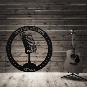May include: Black and white logo with a vintage microphone and floral accents. The logo is in a circle with the text "Mixtape Records Est. 2023". A brown acoustic guitar is in the foreground.