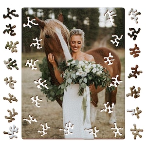 Peut inclure: Un puzzle en bois rectangulaire représentant une photographie d'une personne en robe blanche tenant un bouquet de fleurs blanches et de verdure à côté d'un cheval brun avec une liste blanche sur la tête. Les pièces ont des formes irrégulières.