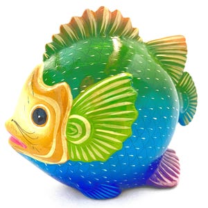 May include: A hand-painted, wooden fish figurine. The fish features a vibrant color palette, with a blue body, green back, and yellow head. The fins are green and yellow, and the tail is purple. The fish has a detailed scale pattern.