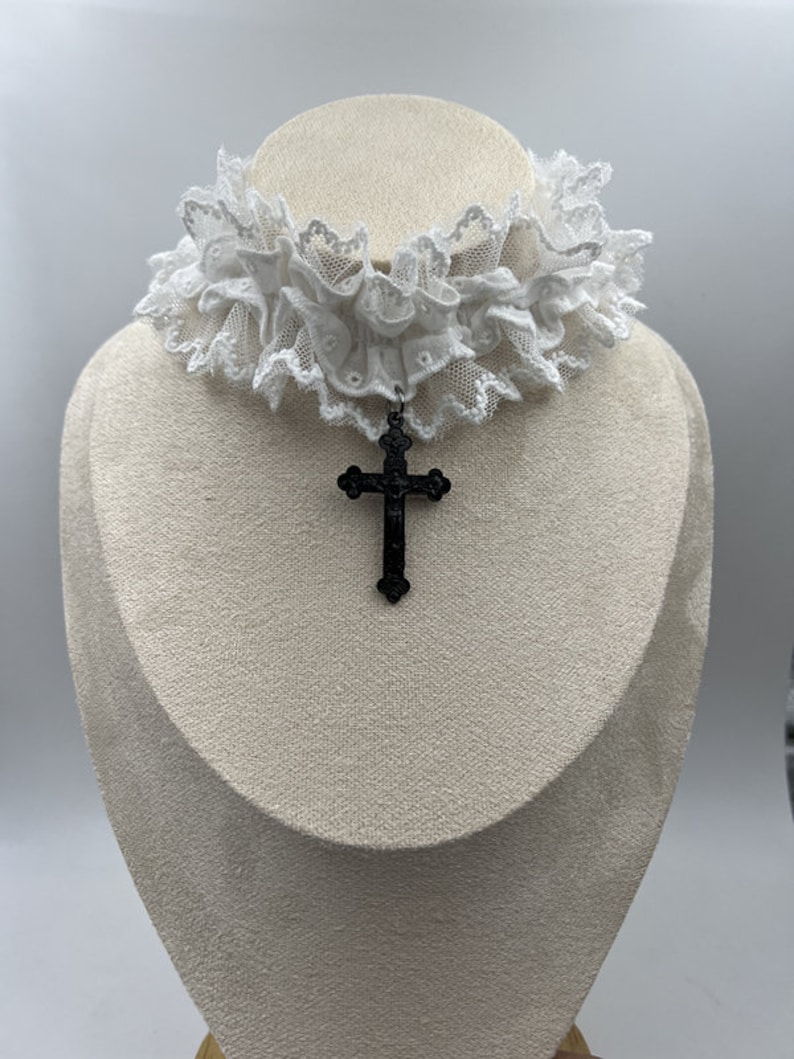 May include: White lace choker with a black cross pendant.
