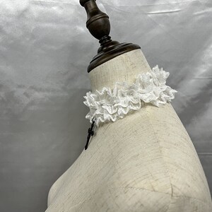 May include: White lace choker with a black pendant on a white mannequin.