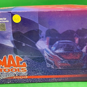 May include: A red, white, and blue 1:24 scale funny car model in a box with the words "MAC TOOLS Collector's Club 2000" on the front. The box is purple and blue with a picture of the car on the front.