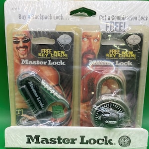 May include: A display featuring two Master Lock combination locks. The lock on the left is a black carabiner style lock. The lock on the right is a silver combination padlock. Both locks are advertised as being free with purchase of a backpack lock. The display also features the text "FREE WCW KEY CHAIN!" and "Master Lock."