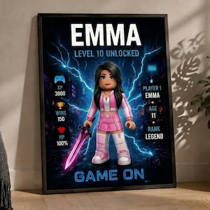 May include: A framed poster featuring a digital avatar character with long dark hair, wearing a pink and white outfit, holding a glowing purple sword. The background shows blue lightning effects, game statistics, and the text EMMA, LEVEL 10 UNLOCKED, GAME ON.