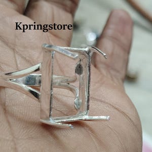 Puede incluir: Engaste de anillo de plata con bisel rectangular para una piedra preciosa. El anillo está diseñado con una banda simple y elegante.