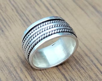 May include: A silver ring with a braided design. The ring is wide and has a smooth, polished finish.