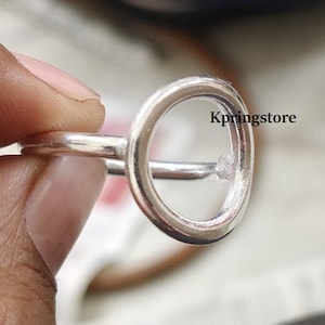 Op de afbeelding: Een zilveren ring met een groot, open cirkelontwerp. De ring is gemaakt van twee banden die aan de boven- en onderkant van de cirkel zijn verbonden.