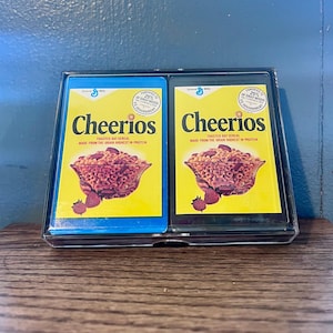Speelkaarten met Cheerios-thema in een doorzichtige plastic hoes. Ontwerp van General Mills-cheergranendoos, standaard speelkaarten