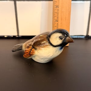 May include: A white ceramic mug with a black handle and the text "But First, Coffee" in a black, handwritten-style font. The mug is on a white surface.