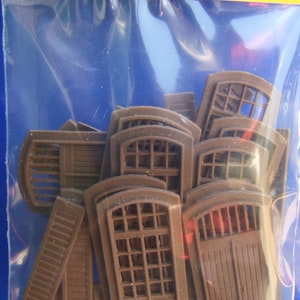 May include: A plastic bag containing brown plastic model window and door pieces. The pieces are of various sizes and shapes, including arched windows, rectangular windows, and doors.