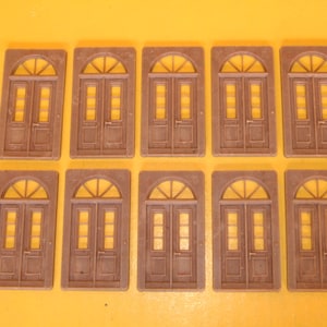 May include: Ten brown wooden double doors with arched windows and decorative trim. The doors are arranged in two rows of five.