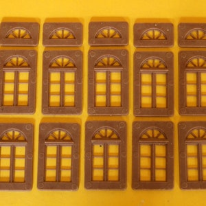May include: A set of 12 brown plastic window frames with arched tops and a grid pattern. The frames are arranged in four rows of three.