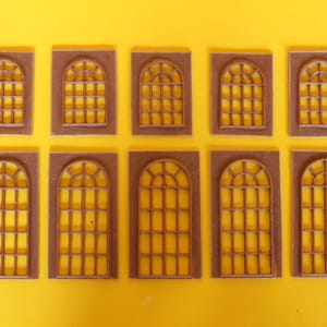 May include: Ten brown wooden window frames with arched tops and a grid pattern. The frames are arranged in two rows of five.