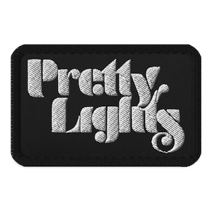 Op de afbeelding: Zwarte geborduurde patch met witte tekst "Pretty Lights".