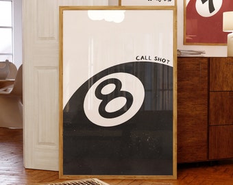 May include: A black and white poster with a black eight ball and the text "Call Shot" in white. The poster is framed in wood and hanging on a wall.