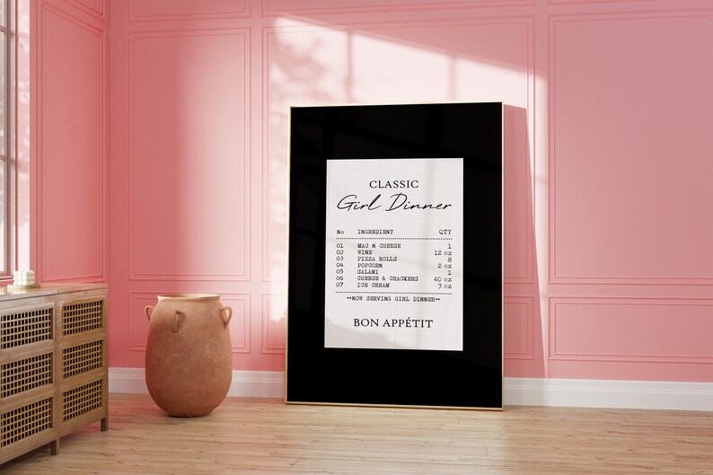 May include: A black framed print with a white background and black text that reads "CLASSIC Girl Dinner" and lists ingredients and quantities for a meal. The text includes "Mac n Cheese", "Wine", "Pizza Rolls", "Popcorn", "Salami", "Cherries & Crackers", and "Ice Cream". The print also includes the text "BON APP&Eacute;TIT".