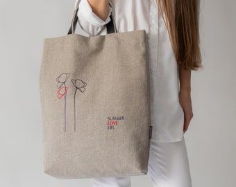 May include: A beige linen tote bag with black handles and a red and blue embroidered design of flowers. The text "SUMMER LOVE LIFE" is embroidered on the bag.