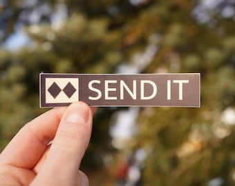 Op de afbeelding: Een zwart-witte sticker met een paar zwarte diamanten en de tekst "SEND IT" in witte letters.