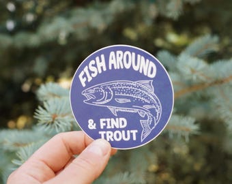Op de afbeelding: Een ronde sticker met een donkerblauwe achtergrond en een witte lijntekening van een forel. De tekst FISH AROUND & FIND TROUT staat in witte hoofdletters, met de kleine tekst @ThinkOutsideCD onder de vis gedrukt.