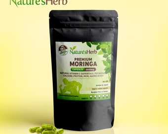May include: A black pouch with a white label that reads "Nature's Herb Premium Moringa Capsules 6600mg". The label also includes the text "Natural Vitamin C Superfood, Potassium, Calcium, Protein, Iron, Amino Acids". The pouch is sitting on a yellow surface with green capsules scattered in front of it.