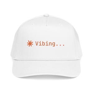 May include: A white baseball cap featuring an embroidered orange asterisk symbol followed by the text "Vibing..." in orange lettering centered on the front panel. The cap has a structured crown, a curved brim, and a button on the top center.