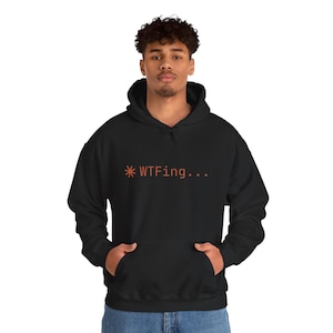 Puede incluir: Sudadera con capucha negra con un bolsillo delantero y texto naranja que dice "*WTFing...". La sudadera está hecha de un material suave y tiene una capucha con cordón.