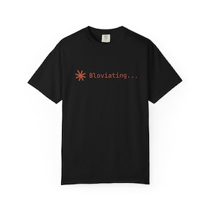 Puede incluir: Camiseta negra con un gráfico color óxido y el texto "Bloviating...". El gráfico incluye un asterisco estilizado. La camiseta tiene mangas cortas y cuello redondo.