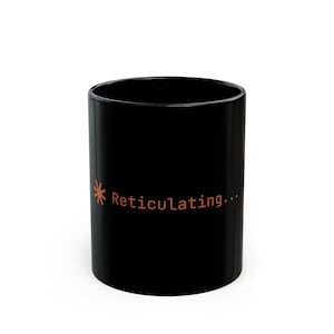 May include: Black ceramic mug with the text "Reticulating..." in orange. The mug has a simple, cylindrical shape and a glossy finish. An orange asterisk is next to the text.