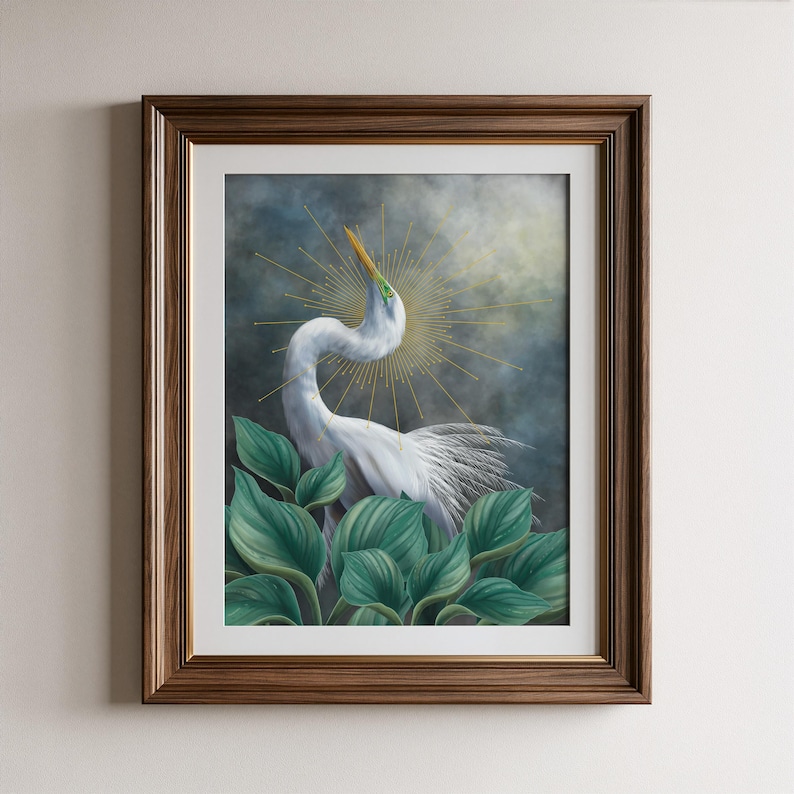Pode incluir: Uma impress&atilde;o de arte emoldurada apresentando uma gar&ccedil;a branca com pesco&ccedil;o longo e bico amarelo, cercada por grandes folhas verdes. Atr&aacute;s da ave h&aacute; um c&eacute;u escuro e nublado e um design de halo dourado. A moldura &eacute; de madeira castanha.