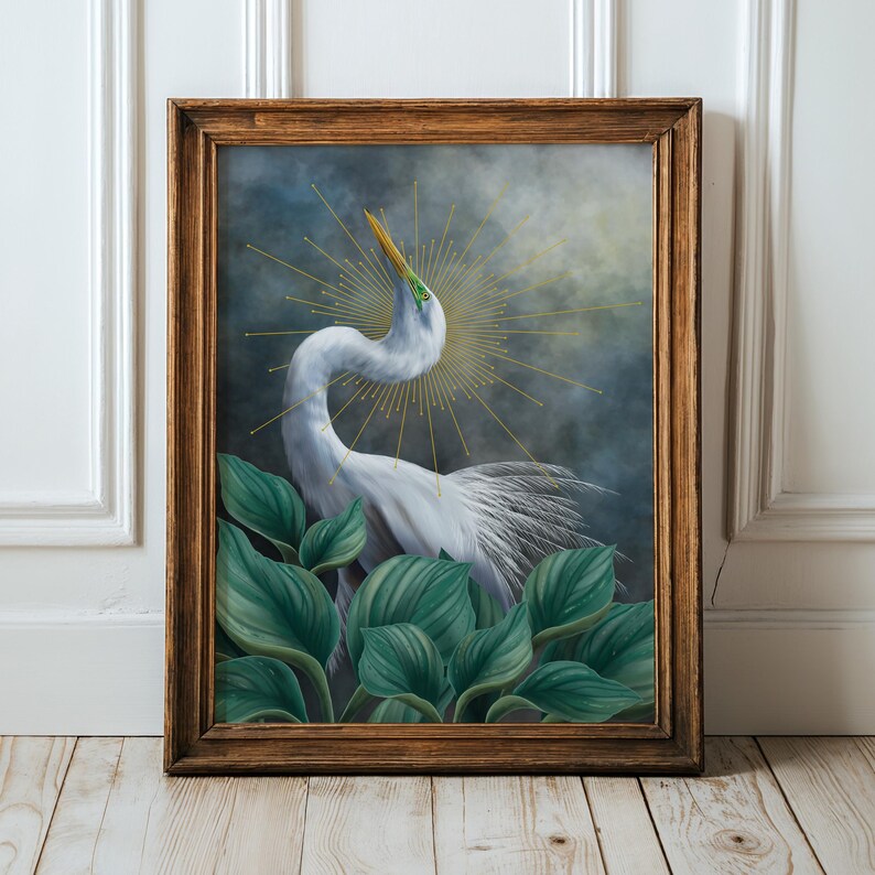 Pode incluir: Uma pintura emoldurada de uma gar&ccedil;a branca com pesco&ccedil;o longo e bico amarelo, rodeada por grandes folhas verdes. A ave est&aacute; posicionada contra um fundo escuro e nublado com um halo dourado de raios de sol irradiando atr&aacute;s da cabe&ccedil;a.