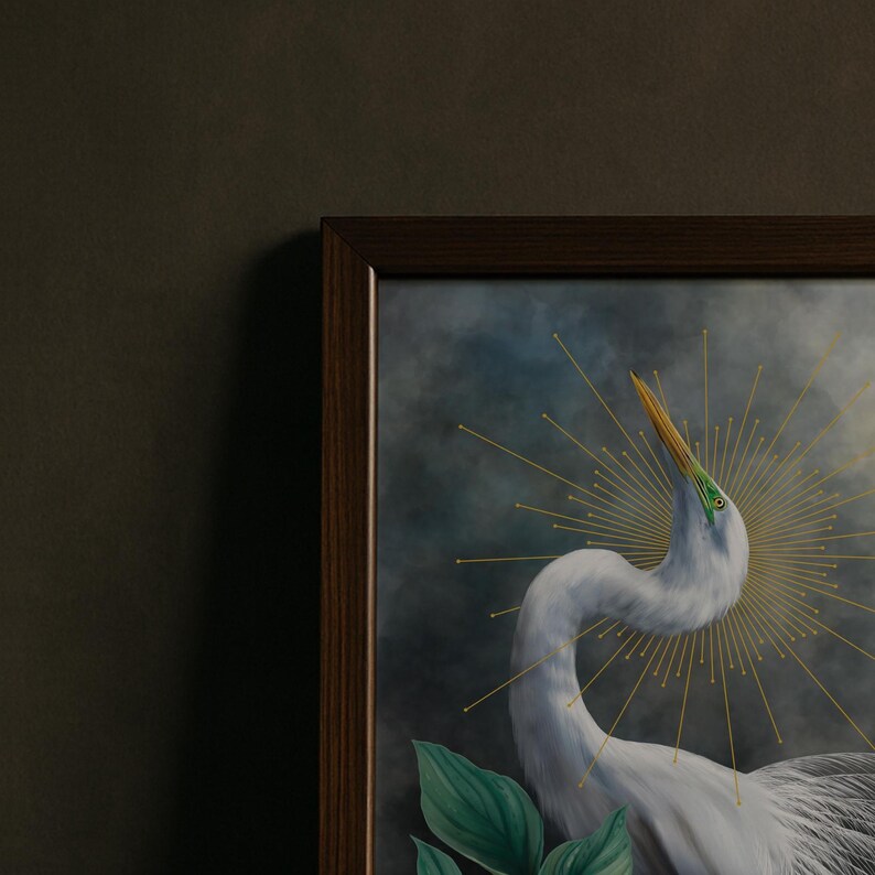 Pode incluir: Uma impress&atilde;o de arte de parede emoldurada apresentando uma gar&ccedil;a branca com um pesco&ccedil;o longo e curvo e um bico amarelo. A ave est&aacute; rodeada por um halo dourado de raios de sol contra um fundo escuro, nublado e melanc&oacute;lico, com folhas.