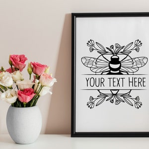 May include: Black and white printable art print featuring a bee with floral accents and the text "YOUR TEXT HERE".
