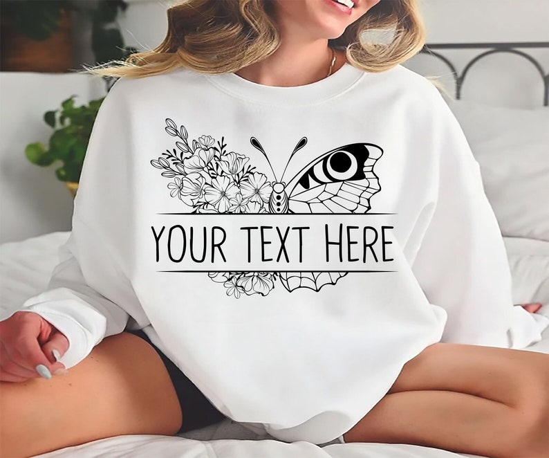 May include: White sweatshirt with a black and white butterfly and floral design. The text "YOUR TEXT HERE" is printed below the butterfly.