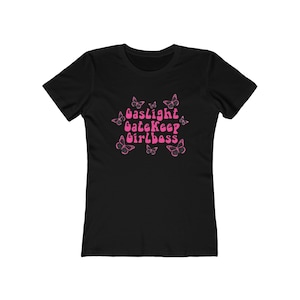 Peut inclure: T-shirt noir avec le texte "Gaslight Gatekeep Girlboss" en lettres roses entouré d'illustrations de papillons roses.