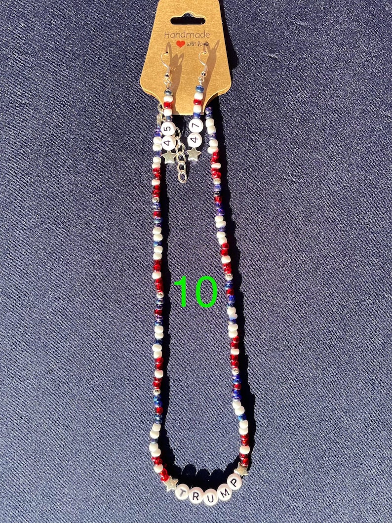 K&ouml;nnte beinhalten: Eine rot-wei&szlig;-blaue Perlenkette mit dem Wort "TRUMP" in silbernen Perlen. Die Kette h&auml;ngt an einer Karte mit der Aufschrift "Handgefertigt mit Liebe".