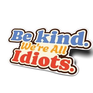 May include: A sticker with the text "Be kind. We're all idiots." in a retro style font. The words are in different colors: "Be" is brown, "kind" is blue, "We're" is orange, "all" is yellow, and "idiots" is red.