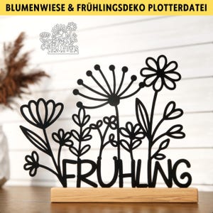 以下が含まれることがあります： 木製の台座に「FRÜHLING」（ドイツ語で「春」）という文字が書かれた、黒いシルエットの花の飾り付け。