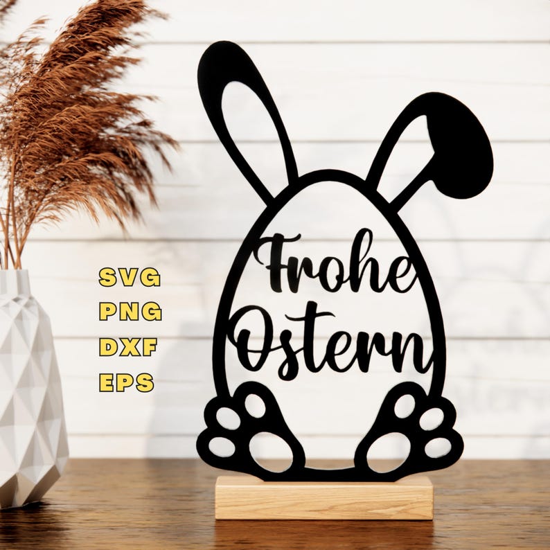 May include: Black silhouette of a bunny rabbit holding an egg with the text "Frohe Ostern" on it. The bunny is standing on a wooden base.
