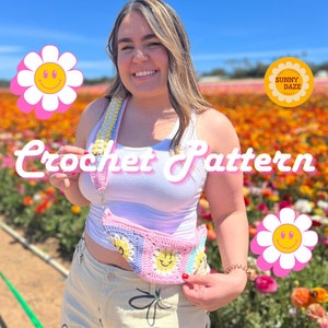 May include: A woman wearing a white vest top and white shorts with a pink, yellow and blue crochet bag featuring a smiley face design. The bag is worn as a crossbody bag. The woman is standing in a field of flowers. The text "Crochet Pattern" is written in pink letters across the image.